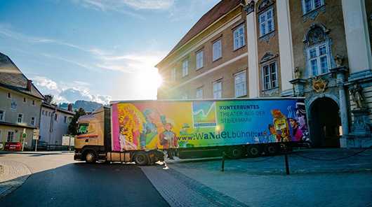 LKW Planen: LKW mit bunter Plane vor historischem Gebäude. Werbung für Wandelbühne Steiermark.
