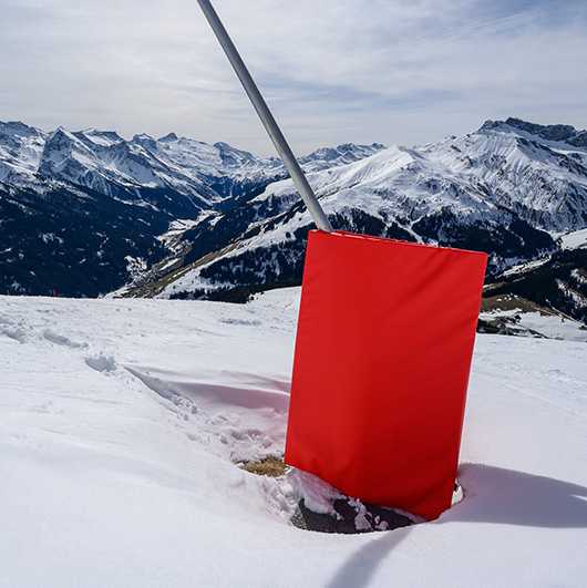 Rote Prallschutzmatte im Schnee. Schutz vor Verletzungen im Wintersport.