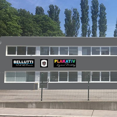 Bellutti Out of Home, Plakativ Green Printing Standort Wien. Bürogebäude mit Zaun.