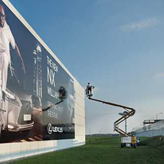 Außenwerbung: Montage eines Lexus NX Werbebanners. Arbeiter auf Hebebühne. Großflächige Außenwerbung.