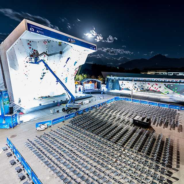 Kletterevent in Innsbruck: Kletterwand, Bühne und Sitzplätze unter dem Nachthimmel. Venuebranding Klettern.