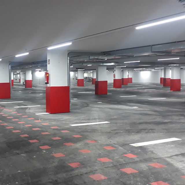 Tiefgarage mit Prallschutz an Säulen. Rote Markierungen am Boden. Sicheres Parken.