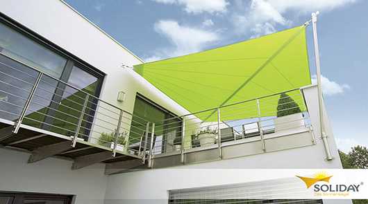 Modernes Haus mit grünem Sonnensegel auf dem Balkon. Sonnenschutz.