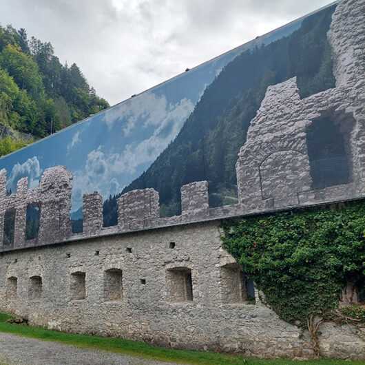 Textile Architektur Burg Ehrenberg: Fassade mit Bergpanorama und Burgruine.