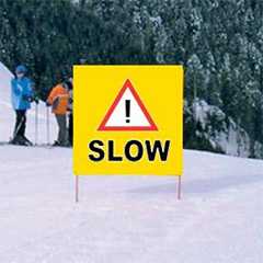 Gefahrenbanner: Gelbes Warnschild SLOW auf Skipiste. Sicherheit im Sport.