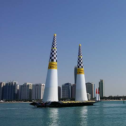 Event: Luftrennen im Freien mit Pylonen im Wasser vor Skyline.