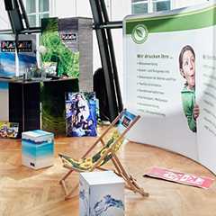 Präsentationssysteme Messe: Messestand mit Werbedisplays, Faltdisplays, bedruckten Hocker und Liegestuhl.