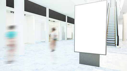 Karriere: Leere Werbefläche in Shopping Mall. Rolltreppe im Hintergrund.