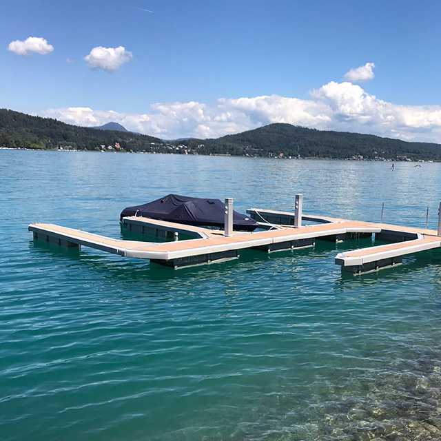 Bootsteg mit Prallschutz am See. Boot liegt am Steg. Bootstegleisten schützen Boote.