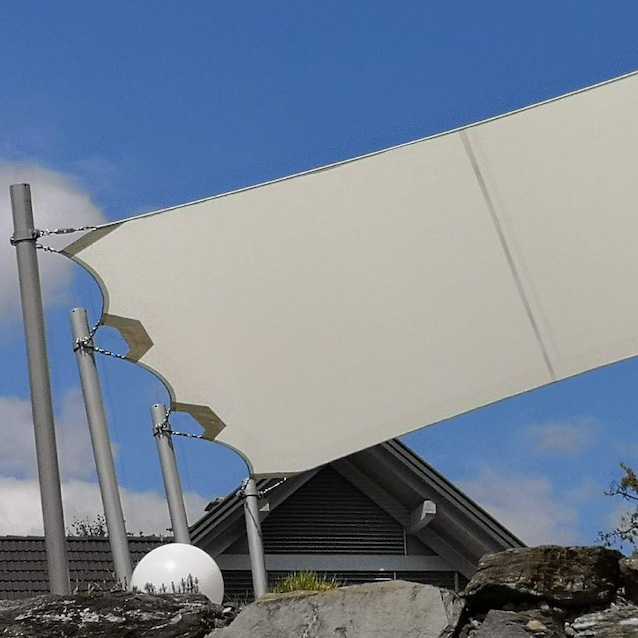 Weißes, quadratisches Sonnensegel mit Stahlmasten gegen blauen Himmel. Diverse Sonnensegel.