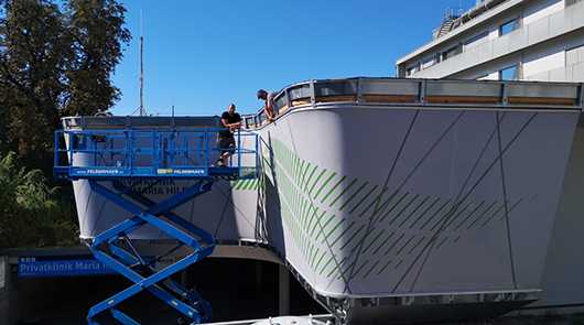 Montage: Arbeiter auf Hebebühne bei Fassadenmontage. Transport und Installation.