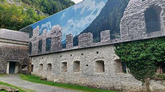 Technische Konfektion: Fassade mit Bergpanorama und Mauerwerk. Technische Textilien für Bauprojekte.