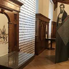 Ausstellungen: Museum mit Holzvertäfelung, Textwand und historischem Portrait.