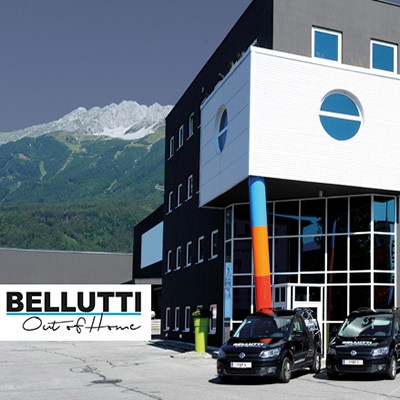 Bellutti Standort Innsbruck: Modernes Gebäude mit Firmenwagen vor Bergkulisse.
